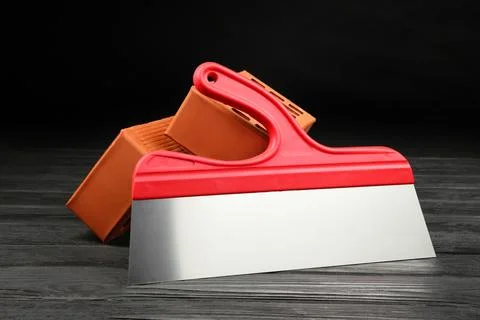 Red bricks and putty knife on wooden table. Building material Stock Photos