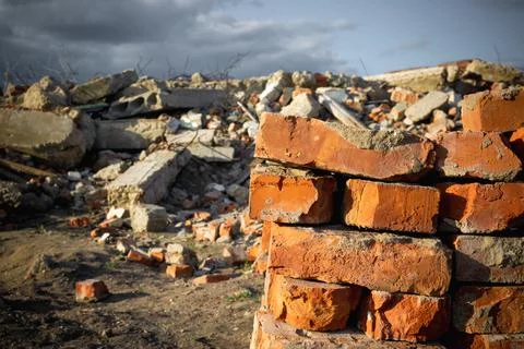 Red bricks on the background of a destroyed building and blue sky. Stock Photos