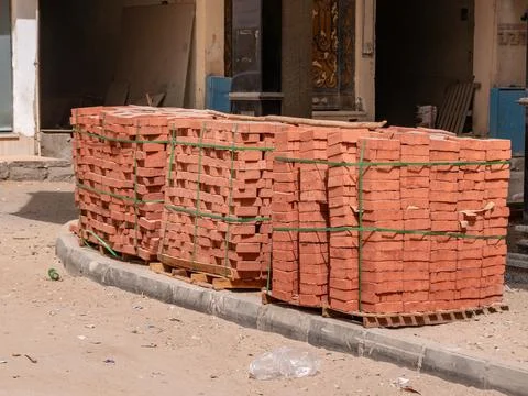 Red bricks packed in piles are stored outdoors. Construction material. Stock Photos