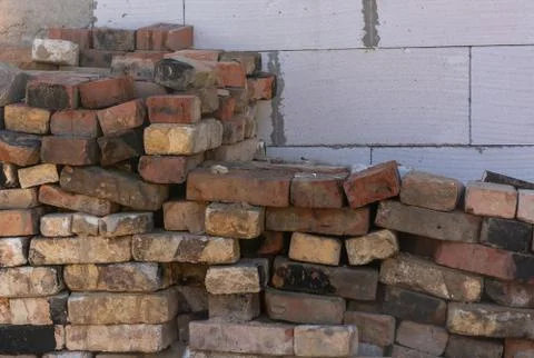 Red bricks piled against a white wall close up Stock Photos
