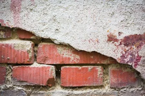 Red bricks showing through white broken plaster Stock Photos