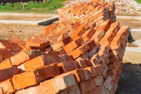 Red bricks stacked at a construction site. Construction of brick houses. Stockfoto's