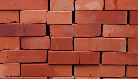 Red bricks stacked on a pallet crack under their own weight Stock Photos