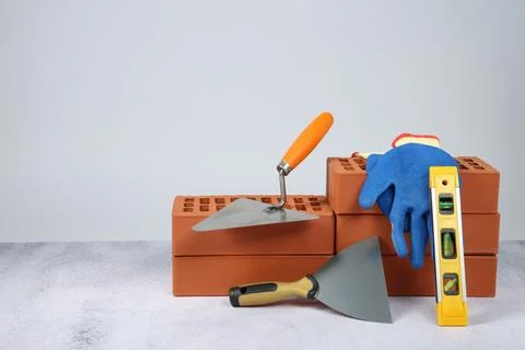 Red bricks, trowels, gloves and building level on textured table against li.. Stock Photos