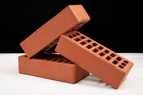 Red bricks on white wooden table. Building material Stock Photos