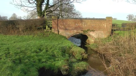 Red bridge over stream with stile rural setting Stock Footage 46457061