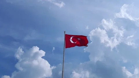 Red bright flag of Turkey flutters on a flagpole high above the ground against Stock Footage 242846868