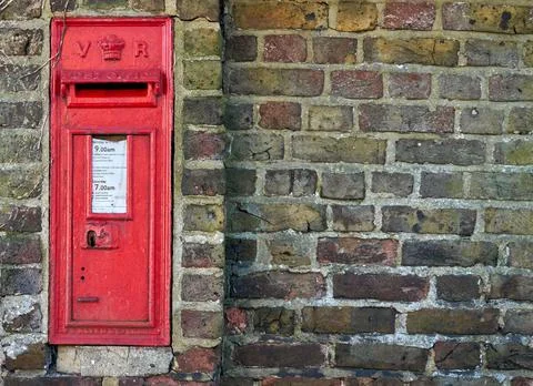 A red British post box in a wall with the royal cypher VR Stock Photos