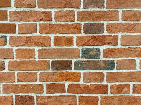 Red, brown background of uneven brickwork with lines of cement joints. Stock Photos
