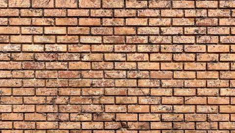 Red-brown weathered solid brick wall with traces of dirt, rugged surface. Stockfoto's