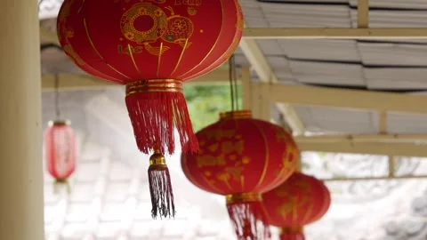 Red buddhist lanterns with gold trim and tassels sway gently under a covered ver Stock-Footage 343041207