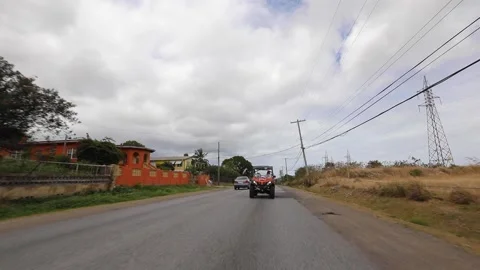 Red buggy driving through the island road with houses, trees and fields pass by. Stock Footage 202122533