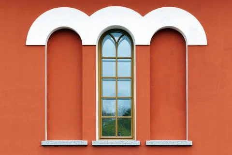 Red building facade features a white rounded arches and a tall window and n.. Fotos de archivo