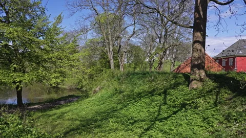 Red Building Framed by Spring Trees and Still Water Vidéo 309425181