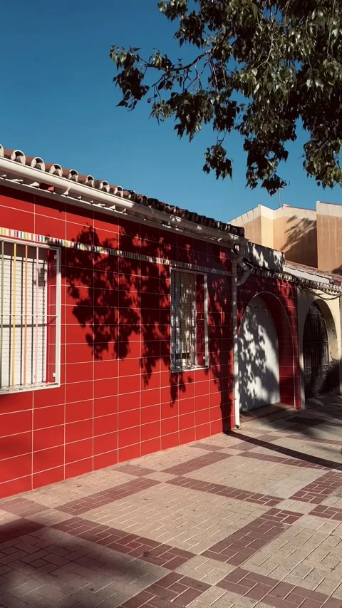 Red building in Spain with tree leaves' shadows on it. Vertical video Stock Footage 240731839