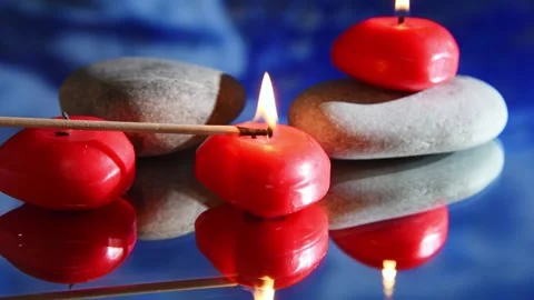 Red burning candles in water, reflection of waves on blue background. Stock Footage 168369682