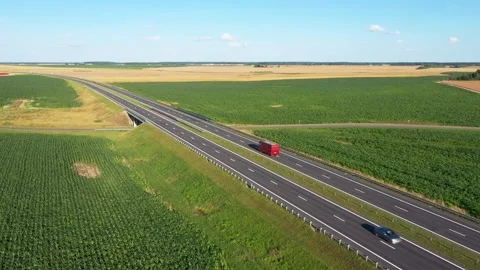 Red bus moving on highway through green fields under blue sky Stock Footage 314616175