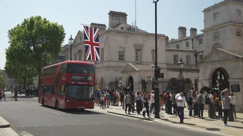 Red bus passing Dover House and tourists on Whitehall, London, England Stock Footage 243077688