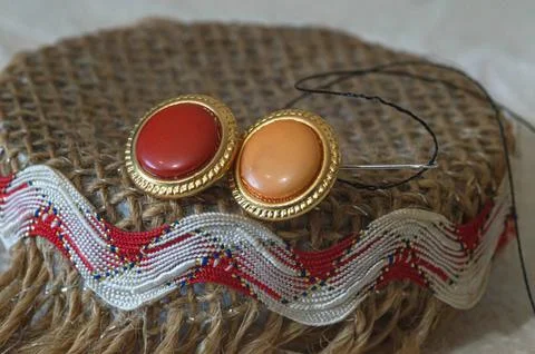 A red button and a beige button on a brown string background with a red bell Stock Photos