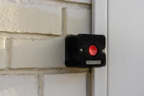 Red button in black box on white brick wall Stock Photos