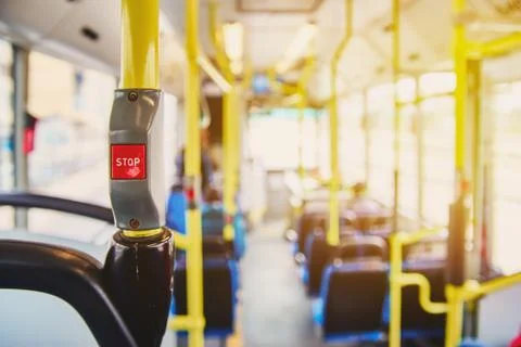 Red button STOP on the bus. Bus with yellow handrails and blue seats. Photo w Stock Photos