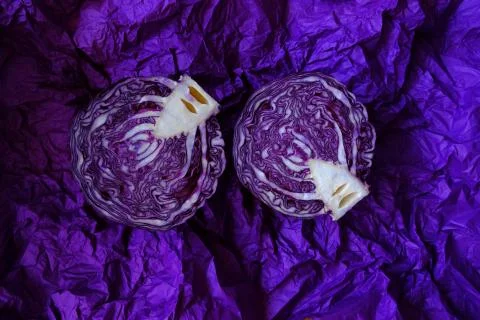 Red cabbage cut pieces close-up on a bright crumpled purple background. Stock Photos