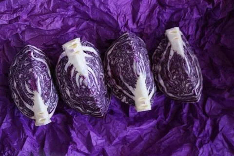 Red cabbage pieces close-up on a bright crumpled purple background Stock Photos