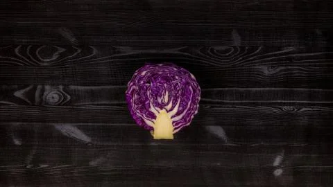 Red cabbage split in half with the original pattern on a black rustic background Stock Photos
