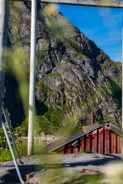 Red Cabin at Base of Dramatic Mountain Cliff in Lofoten Norway Фото
