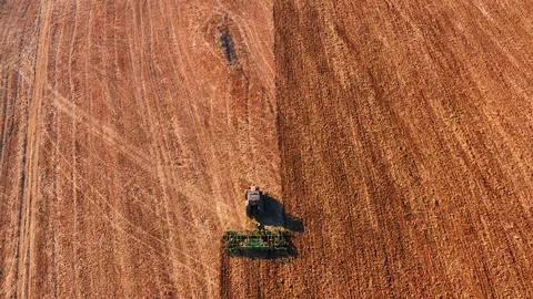 Red cabin tractor plowing the field with green plough, aerial view. Stock Footage 107100144