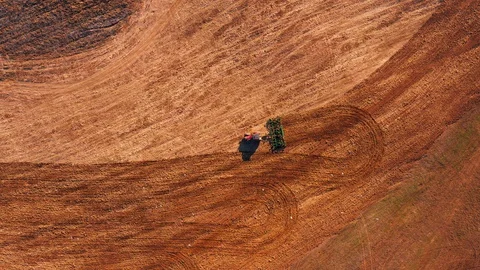 Red cabin tractor plowing the field with green plough, aerial view. Stock Footage 107100194