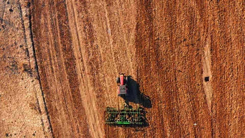 Red cabin tractor plowing the field with green plough, aerial view. Stock Footage 107100252