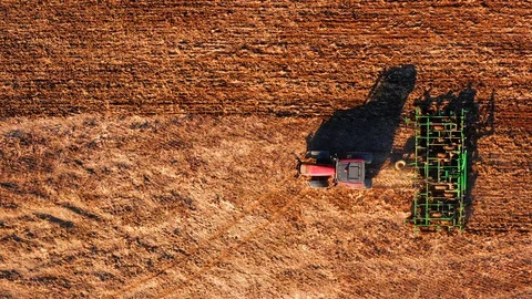 Red cabin tractor plowing the field with green plough, aerial view. Stock Footage 107100399