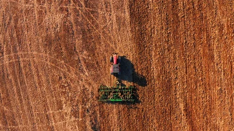 Red cabin tractor plowing the field with green plough, aerial view. Stock Footage 107100428
