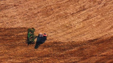 Red cabin tractor plowing the field with green plough, aerial view. Stock Footage 107100527