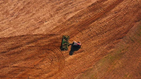 Red cabin tractor plowing the field with green plough, aerial view. Stock Footage 107100546
