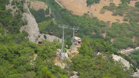 Red cabins move along ropeway above slopes with forests Video stock 141447864