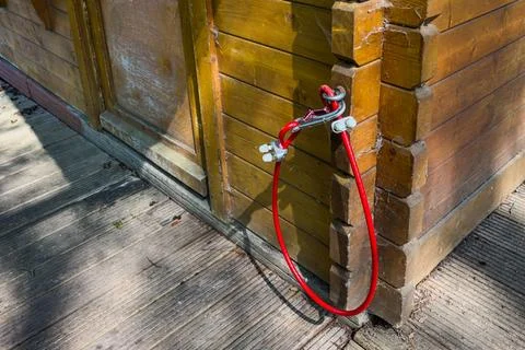 Red cable attached to wooden structure in a sunny outdoor setting Stock Photos