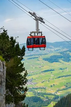 Red cable car ascend a mountain on a bright day, scenic landscape view Stock Photos