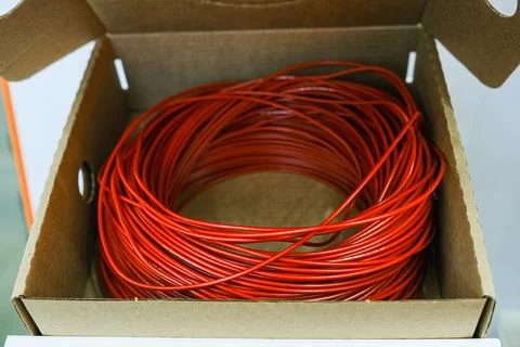 Red cable coil inside carton box for electrical installation. Industrial wire Stock Photos
