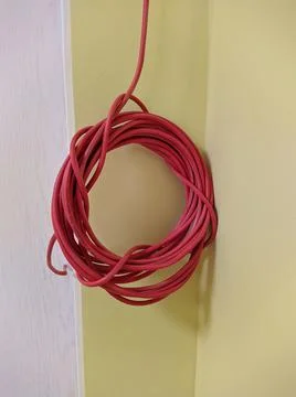 Red cable twisted into a circle hanging from the ceiling Stock Photos