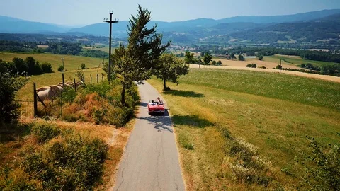 Red cabriolet car driving in typical countryside summer landscape in Tuscany Stock Footage 103215987