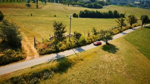 Red cabriolet car driving in typical countryside summer landscape in Tuscany Stock Footage 103216054