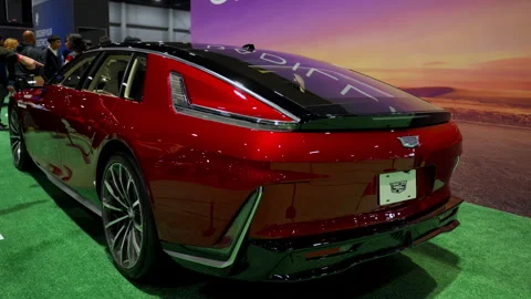 Red Cadillac Celestiq displayed at an auto show exhibition with visitors around Stock Footage 330988683
