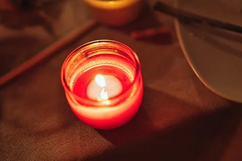 Red candle burning on table creating warm light Stock Photos