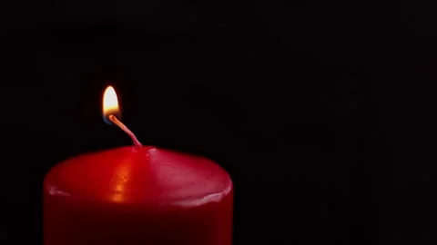 Red candle flickering softly in a dark room creates a warm and inviting atmosphe Stock Footage 295438069