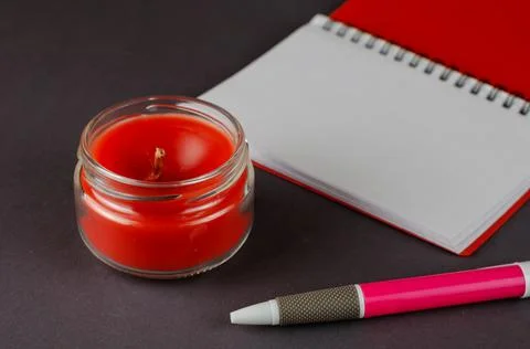 Red candle, open blank notebook and pen on gray background. Stock Photos