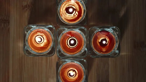 Red candles in glass candlesticks lined up in the shape of a cross. On a wooden Stock Footage 233159504
