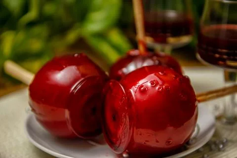 Red candy apple on ceramic plate and glass of cherry liqueur Stock Photos