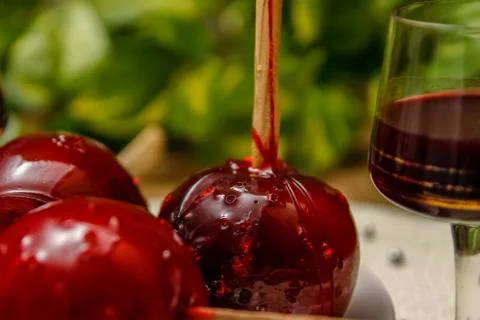 Red candy apple on ceramic plate and glass of cherry liqueur Stock Photos